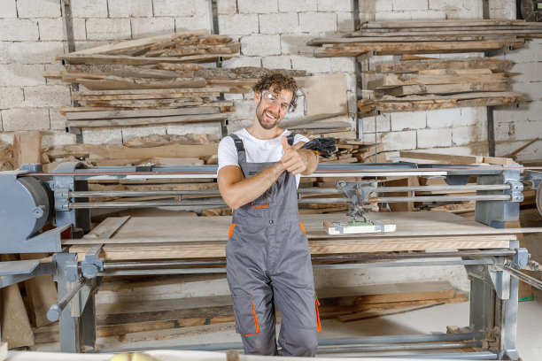 微笑的木匠在他的木工车间里感到满意。图片下载