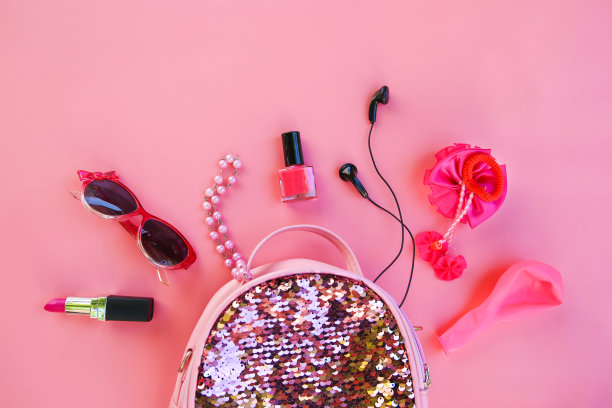 粉色背景的化妆品和女性配件儿童背包。俯视图，平放。图片下载