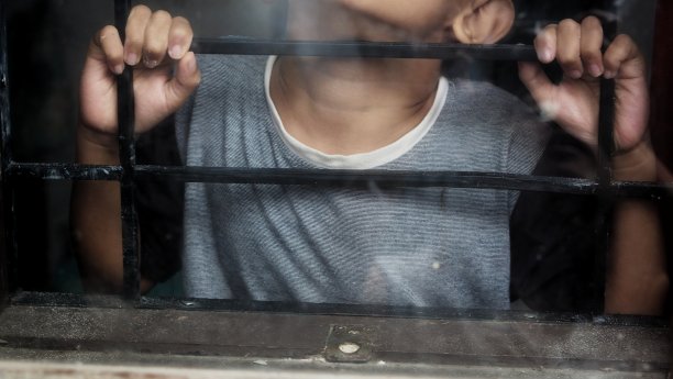 用格子窗。一只手抓住了棚架。那男孩紧抓着棚架。图片下载