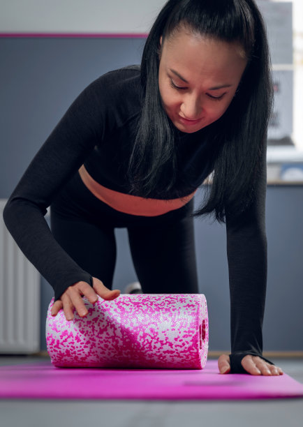一个亚洲女人的垂直照片，在健身房，准备垫子和卷伸展。图片下载