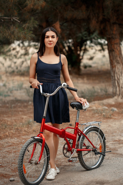 一名身穿深蓝色裙子、肤色黝黑的亚洲女子站在一辆车轮被刺破的自行车旁。出于艺术目的，照片中有一个纹理和一个小的聚焦深度图片下载