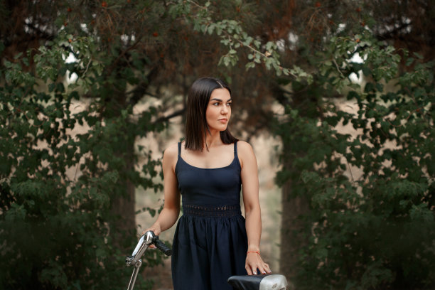 一名身穿深蓝色裙子、肤色黝黑的亚洲女子站在一辆车轮被刺破的自行车旁。出于艺术目的，照片中有一个纹理和一个小的聚焦深度图片下载