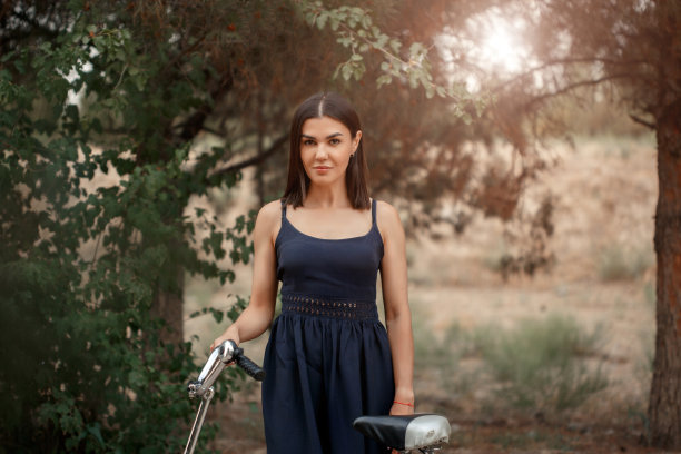 一名身穿深蓝色裙子、肤色黝黑的亚洲女子站在一辆车轮被刺破的自行车旁。出于艺术目的，照片中有一个纹理和一个小的聚焦深度图片下载