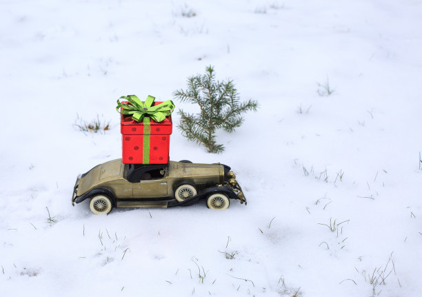 一辆载着圣诞礼物的古董玩具车穿过一个大雪纷飞的冬天。极浅的景深，选择性聚焦在汽车上。图片下载