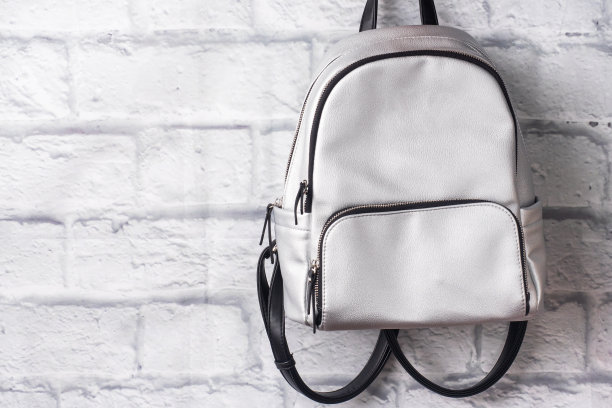 闪亮的银色背包放在砖墙的背景上。本空间图片下载