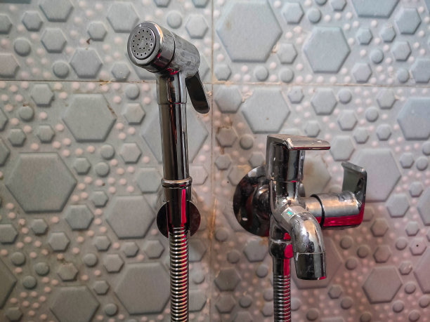 印度马哈拉施特拉邦科尔哈布尔，用银色坐浴盆淋浴的手，或墙上有水龙头的废枪的库存照片。图片下载
