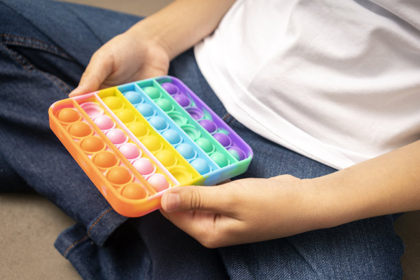 一个没脸的孩子在玩Pop It。Push pop bubble柔性指尖感应玩具提供在青少年手中。简单的酒窝游戏图片下载