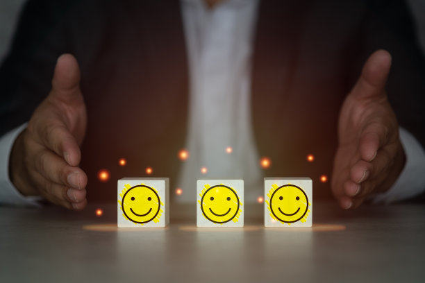 男子张开双手展示木制立方体块形状与图标快乐的脸。最优质的商务服务图片下载