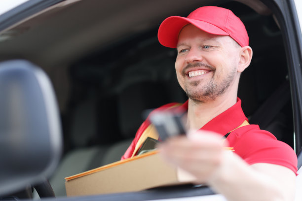 微笑的年轻快递司机的肖像在车窗与手拿盒子图片下载