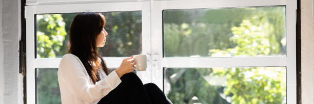 拿着咖啡杯靠近窗户的女人图片下载