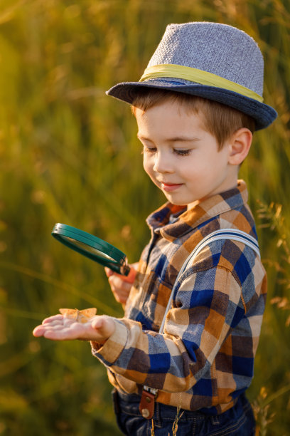 小男孩拿着放大镜在草地上探索大自然图片下载