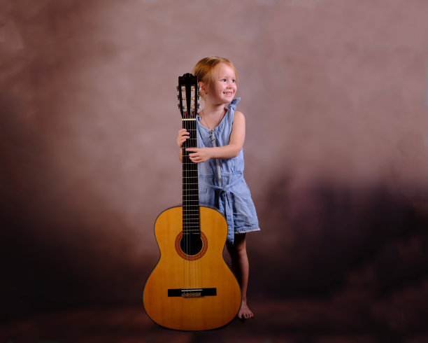 小女孩拿着吉他，脸上带着微笑。儿童教育与就业观念图片下载