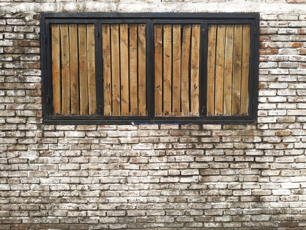 黑色窗框里的棕色木百叶窗，涂着脏兮兮的白色砖墙图片下载