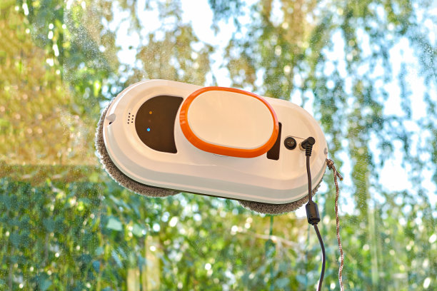 清洁玻璃的机器人。一个机器人真空吸尘器在擦脏窗户。清洁玻璃窗的家庭机器人助手。图片下载