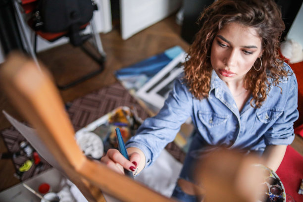 创造性的年轻艺术家在家绘画。图片下载