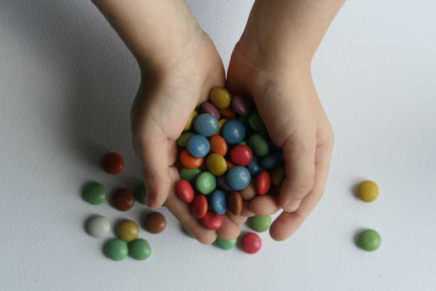 孩子们的手拿着五颜六色的糖果在一个白色的背景图片下载