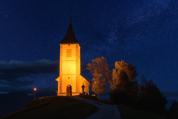 在斯洛文尼亚的山上，被照亮的Jamnik教堂St Primus和felian的风景。风景优美，星空湛蓝，户外旅游背景图片下载