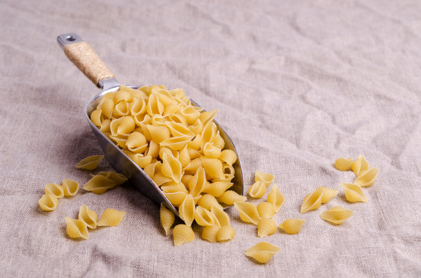 用金属勺舀干意大利面壳图片下载