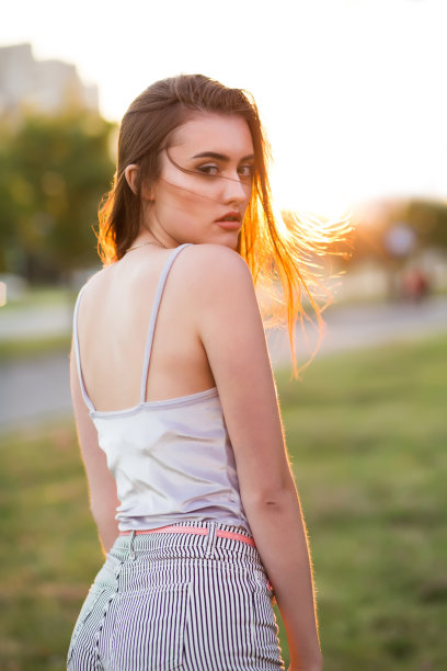 可爱的黑发年轻女子与完美的皮肤在阳光下摆姿势日落图片下载