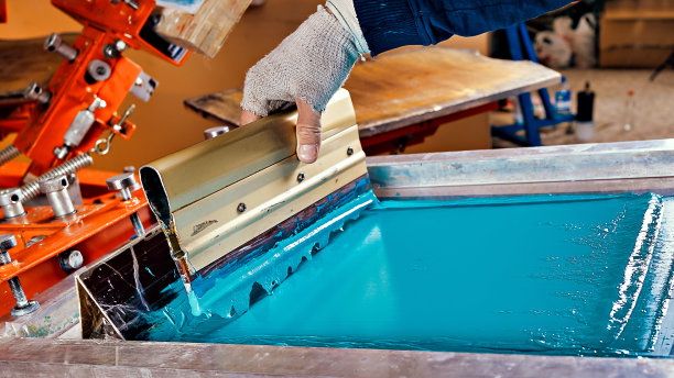 选择性聚焦照片的印刷筛选设备和一个工人。绢印生产。在设计工作室用丝印法在t恤上印刷图像图片下载