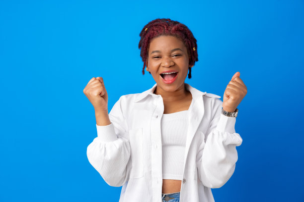 这是一幅在蓝色背景下举起双手的非洲年轻妇女的肖像图片下载
