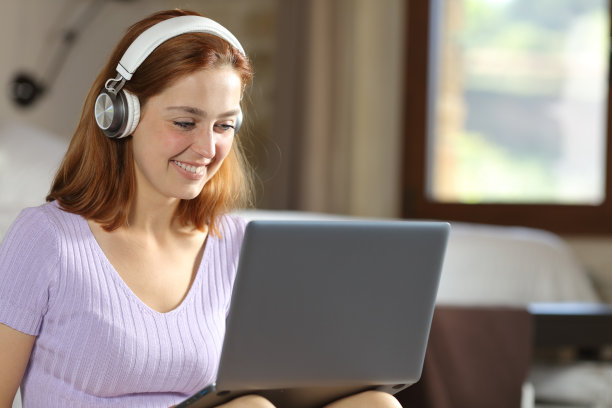 在卧室里用笔记本电脑和耳机的女人图片下载