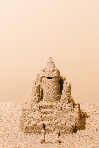 棕色背景上的沙堡。旅行和假期的概念。垂直图像与复制空间。图片下载