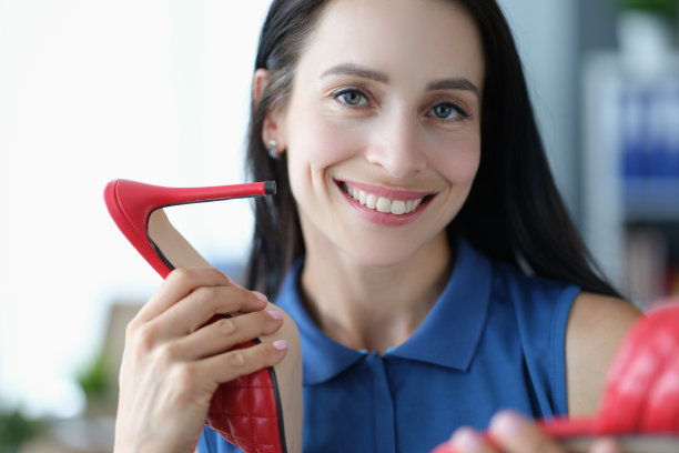 微笑的年轻女子手里拿着红色高跟鞋图片下载