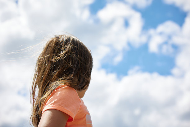 西班牙女孩看天空与多云的天空在背景与一个大的复制空间在背景图片下载