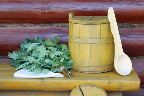 桑拿配件和新鲜的橡木扫帚在黄色的长凳上。图片下载