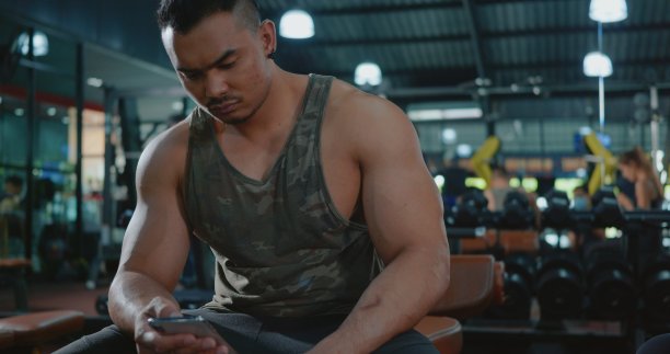 年轻人在健身训练后用智能手机休息图片下载