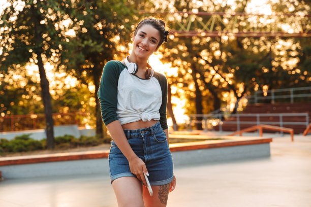 快乐的年轻女孩戴着耳机和手机图片下载