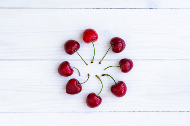 樱桃白色的木质背景。成熟多汁的樱桃果滴在桌上。图片下载