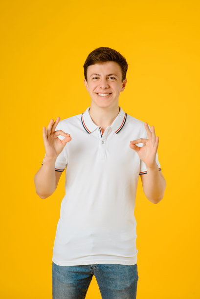 一个年轻的快乐男子的肖像在白色t恤微笑和大笑在黄色图片下载