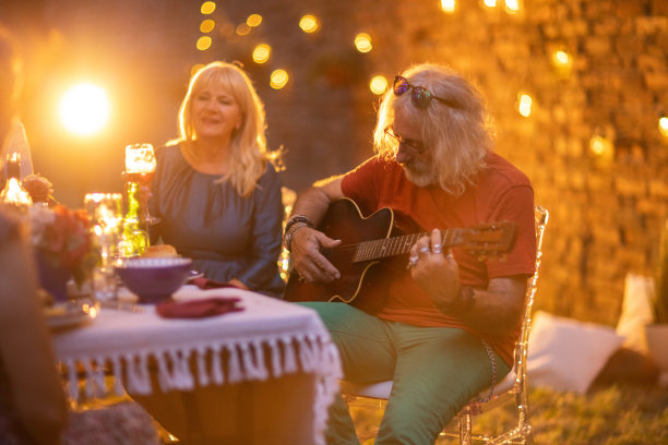 一个老人在游园会上给朋友们弹原声吉他图片下载