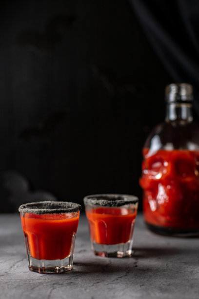 西红柿鸡尾酒装在头骨形状的瓶子和玻璃杯里。万圣节派对喝酒图片下载