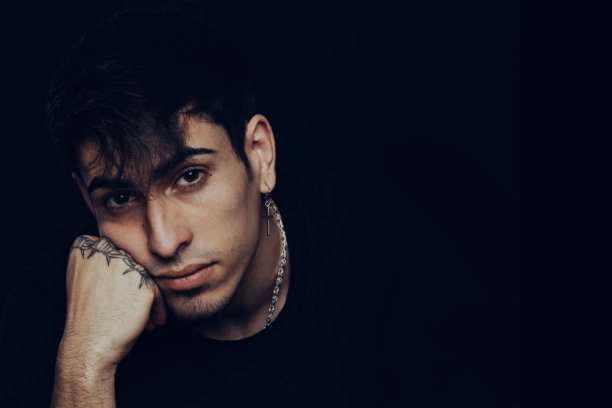 有纹身和耳环的年轻人，表情沉思图片下载