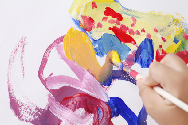 一个亚洲男孩用画笔和水彩画在白纸上图片下载