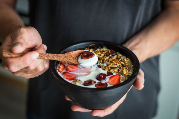 男人手里拿着一把木勺和一个早餐碗图片下载