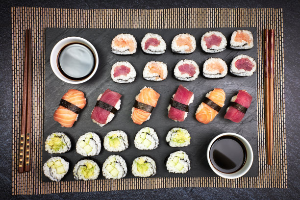 上面的鱼寿司和蔬菜寿司用筷子和酱油在黑板上。东方的食物。日本文化图片下载