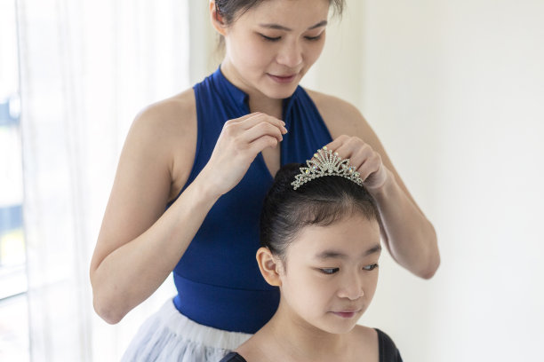 母亲帮助女儿芭蕾舞女在舞蹈室调整发髻图片下载