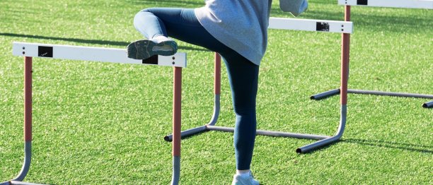 练习中单腿越过跑道栏的运动员图片下载