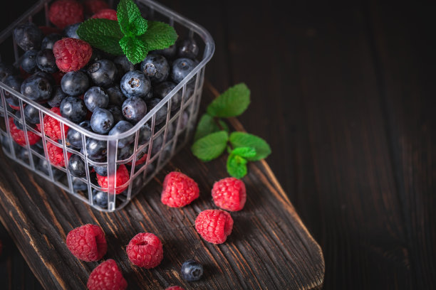 树莓和蓝莓放在篮子里，背景是黑色。夏日与健康的饮食理念。背景与复制空间。有选择性的重点。图片下载