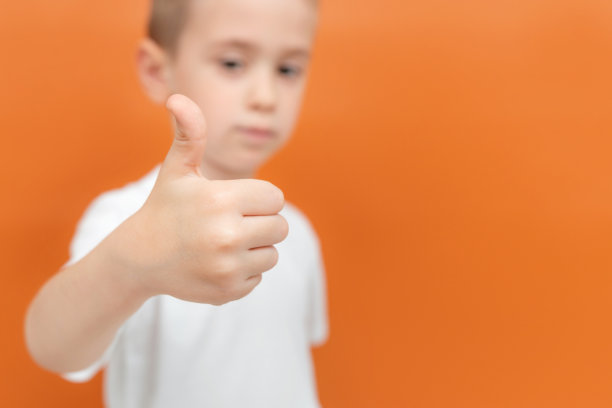 孩子的手举起来。专注于手。小男孩在背景中显得模糊不清。表示同意和喜欢。本空间图片下载