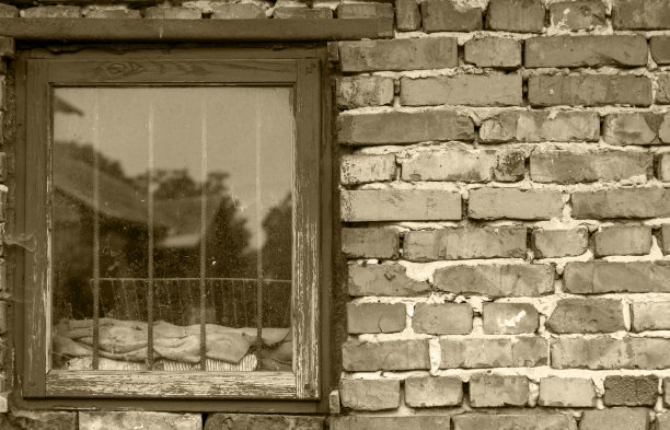 带有木窗的旧砖墙。用金属格栅。在窗户上展示一所老房子。黑色和白色。图片下载