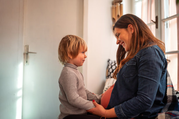 快乐的孩子抱着孕妇的肚子。家庭人的爱情观图片下载