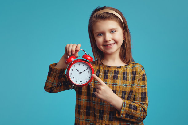 小女孩笑着指着闹钟闹铃，孤立过蓝图片下载