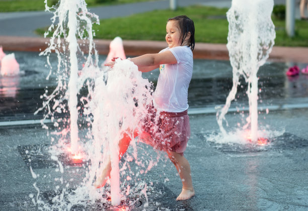一个可爱有趣的小女孩在一个炎热的夏天在公共城市喷泉洗澡。孩子跑着，在水柱和水花间玩耍图片下载