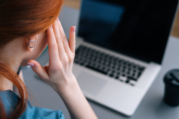 近景的背影疲惫沮丧的年轻女医生在蓝色医疗制服按摩太阳穴，遭受头痛图片下载