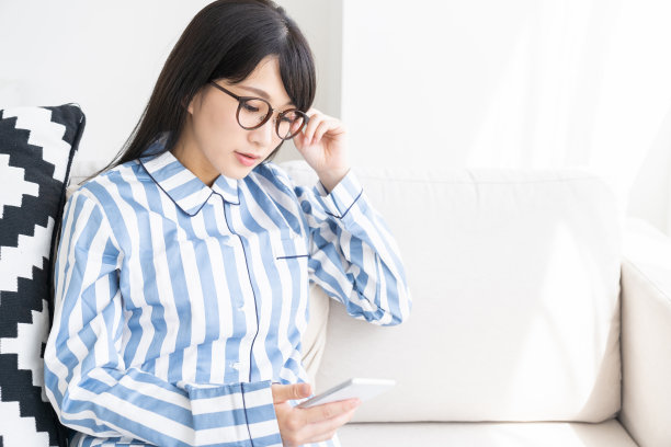 穿着睡衣的亚洲女人，还有智能手机图片下载